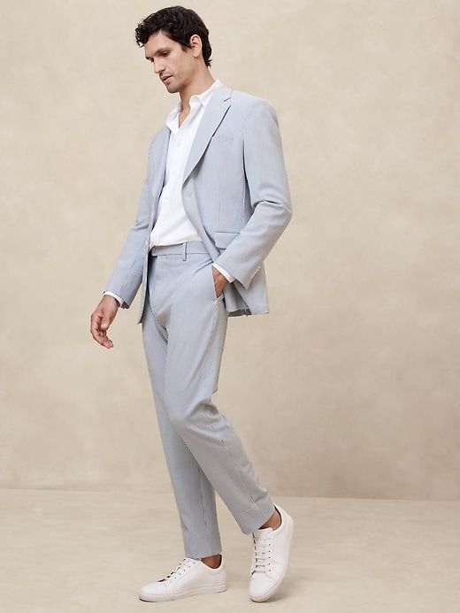 a man in a light blue suit and white shoes