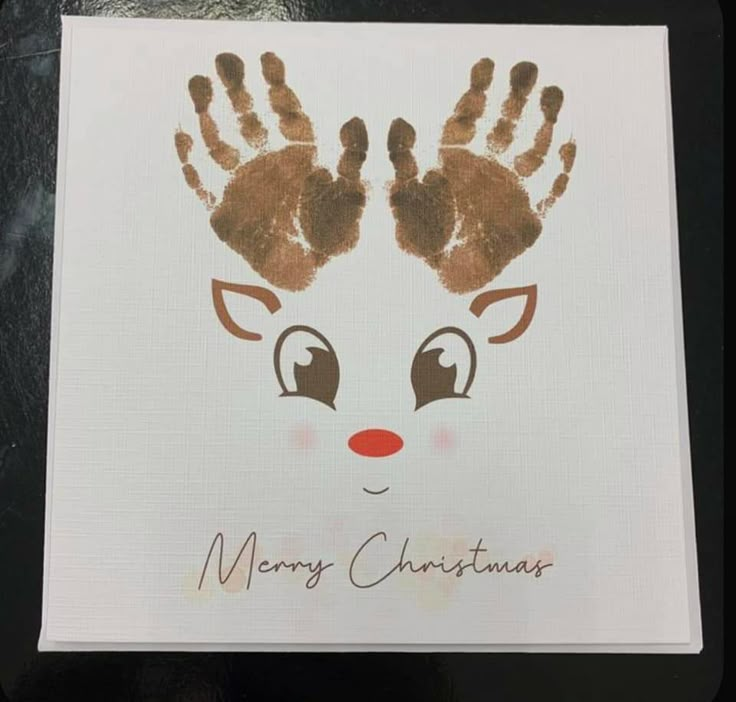 a christmas card with handprints of a reindeer's head and the words merry christmas on it