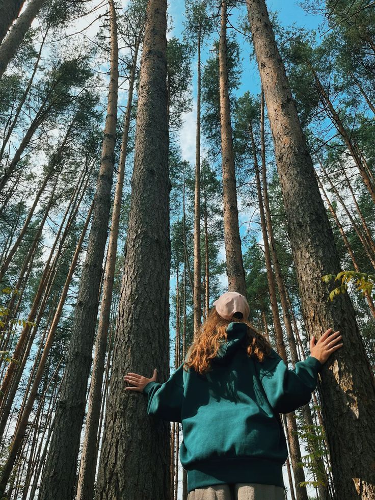 a woman standing in the middle of a forest with her arms spread out to reach trees