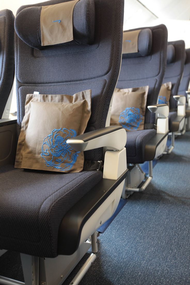 the seats on an airplane are decorated with blue and gold pillows, along with decorative throw pillows