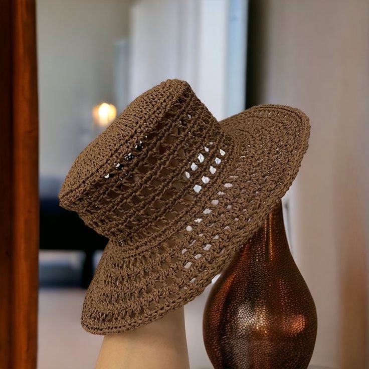 a brown crocheted hat sitting on top of a table next to a vase