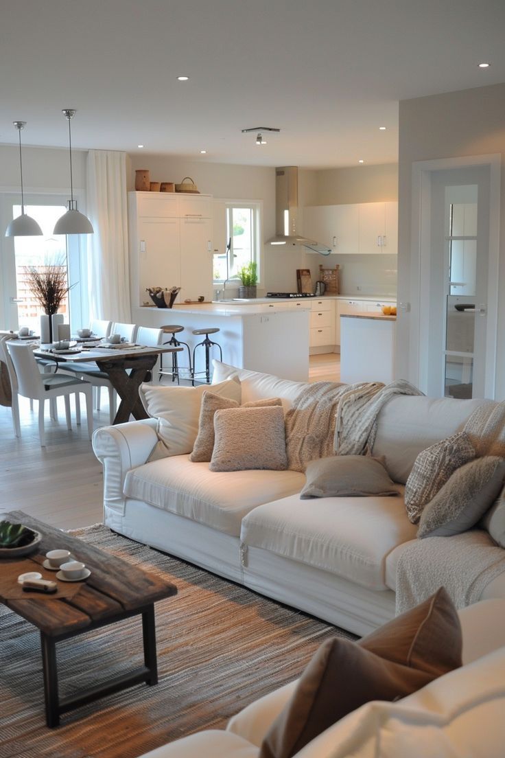 a living room filled with furniture next to a kitchen and dining room table in front of an open floor plan