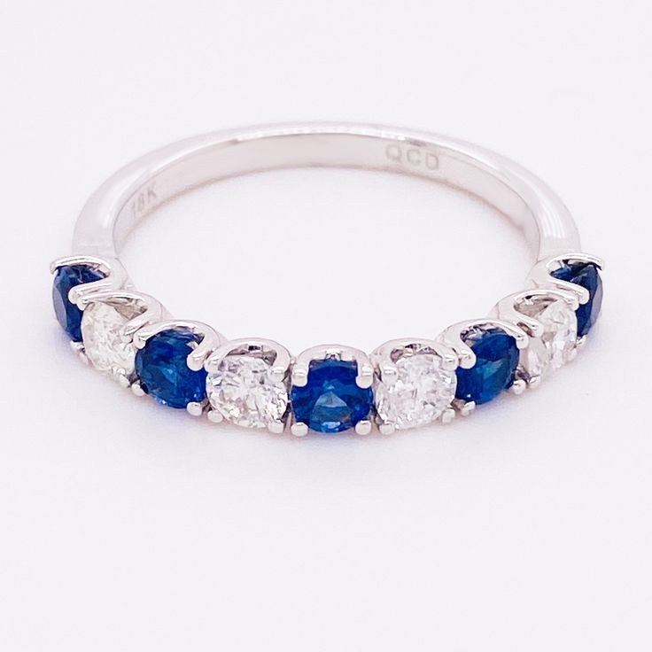 a blue and white diamond ring with five stones on the side, set in 18k white gold