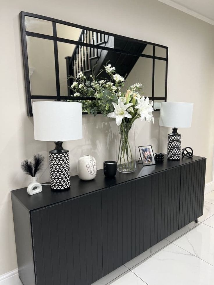 a vase with white flowers on top of a black dresser