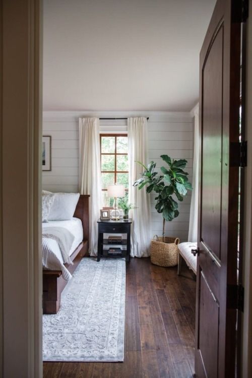 a bedroom with wood floors and white walls, along with a large rug on the floor