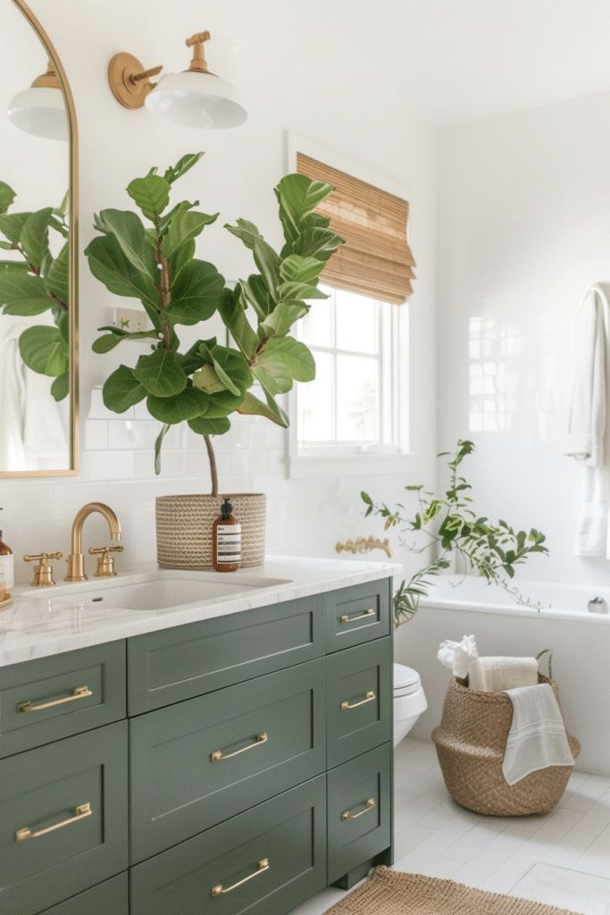 a bathroom with green cabinetry and gold handles on the sink, along with a potted plant