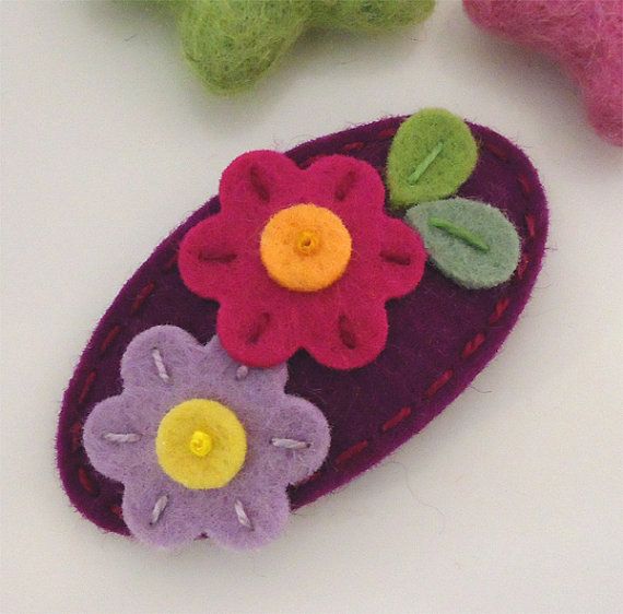 three felt flower brooches sitting on top of a white table next to each other