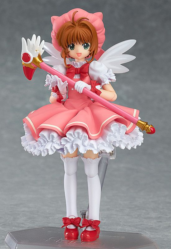 a figurine is holding a wand and wearing a pink dress with white ruffles