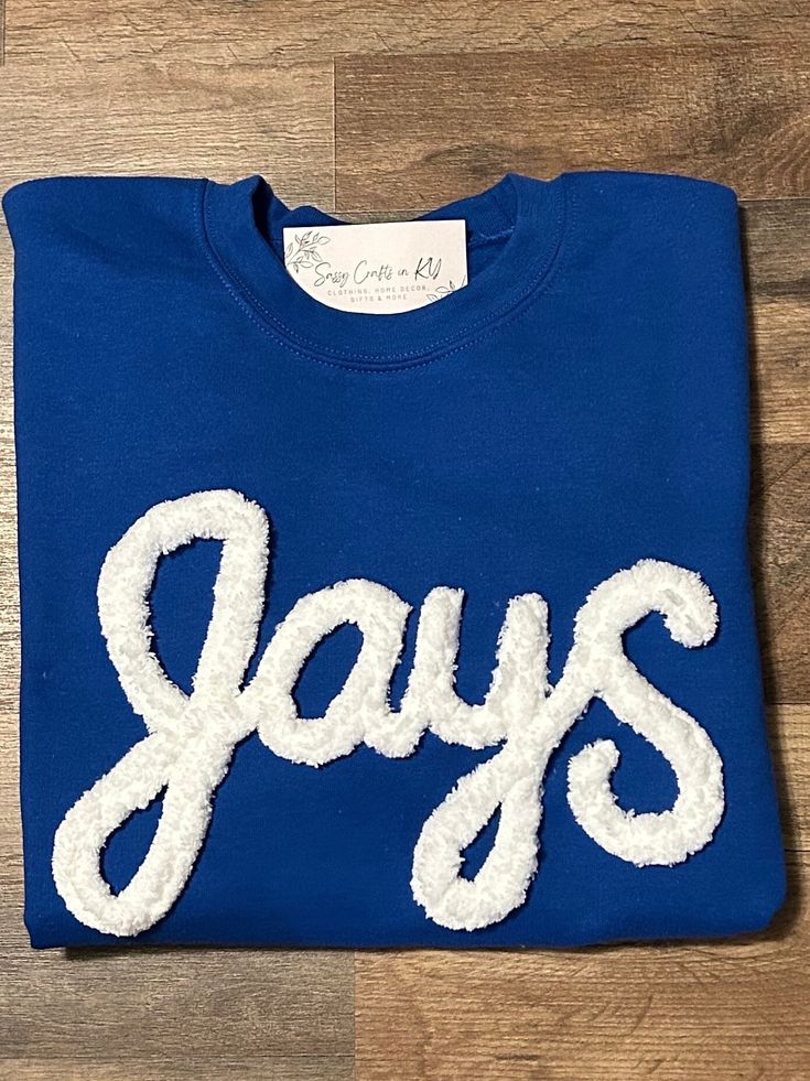 Show your school spirit in this cute sweatshirt. Comfort, casual and loose fitting, made on 50/50 cotton/poly blend shirts.  Embroidered chenille yarn, Jays sweatshirt.   Please message us if you have a custom color request and we will create a separate listing for custom requests.  You can follow us at the below link for chances to win giveaways and to see all of our latest creations.  https://www.facebook.com/groups/710060383256657/?ref=share&mibextid=S66gvF Sporty Tops With Embroidered Logo In French Terry, Cotton Crew Neck Hoodie For College, Varsity French Terry Crew Neck Sweatshirt, Pre-shrunk Crew Neck Sweatshirt For School Spirit, Cotton Crew Sweats For College, College Sweatshirt With Embroidered Logo For School Spirit, College School Spirit Sweatshirt With Embroidered Logo, Cotton Sweatshirt With Letter Print For Fan Gear, Collegiate Blue Letter Print Sweater