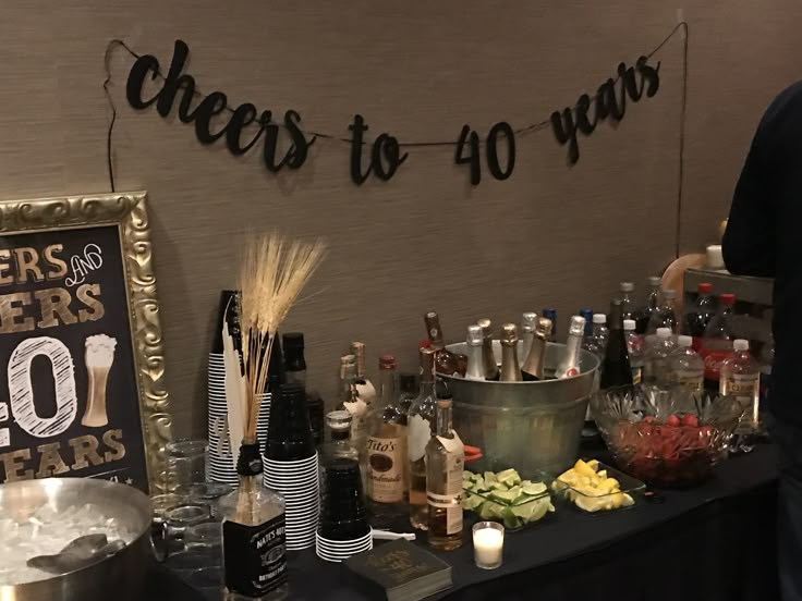 a table with bottles and glasses on it next to a sign that says cheers to 40 years