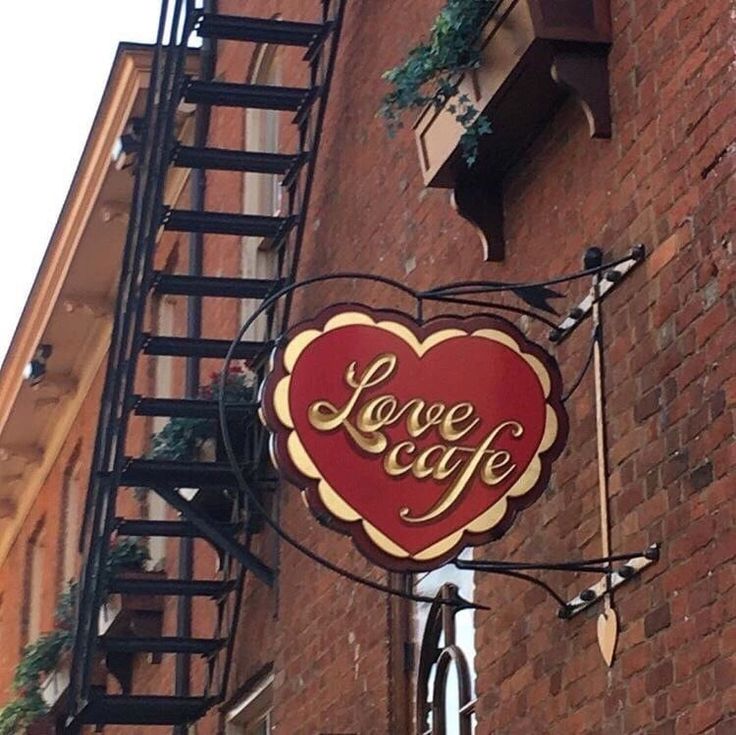 a sign on the side of a building that says love cafe with a red heart