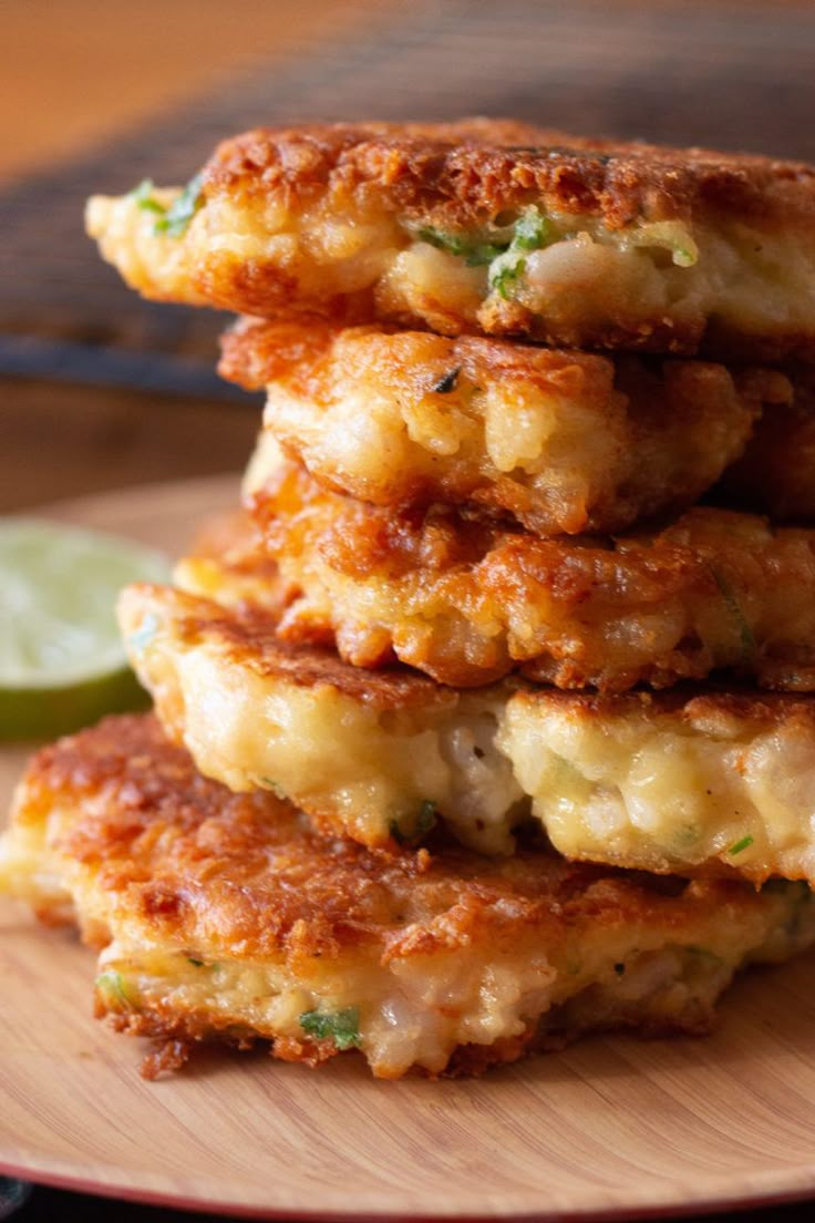 a stack of crab cakes on a plate with lime wedges next to the cake