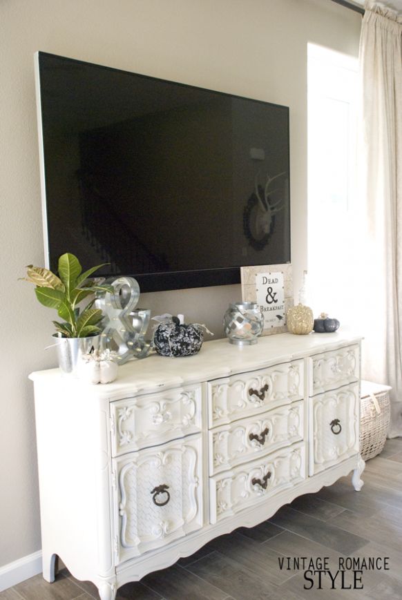 a white dresser sitting in front of a flat screen tv