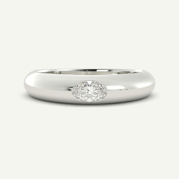 a white gold ring with a round diamond in the center, on a plain surface