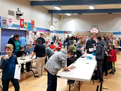 a group of people standing around tables in a gym