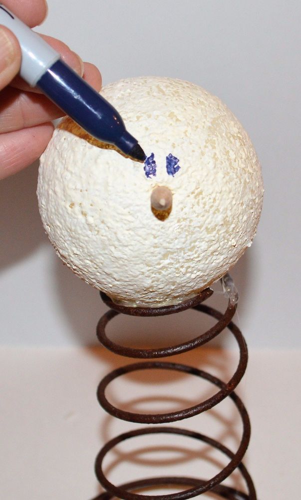 a person is drawing on an egg with a pen and paper machinet in front of it