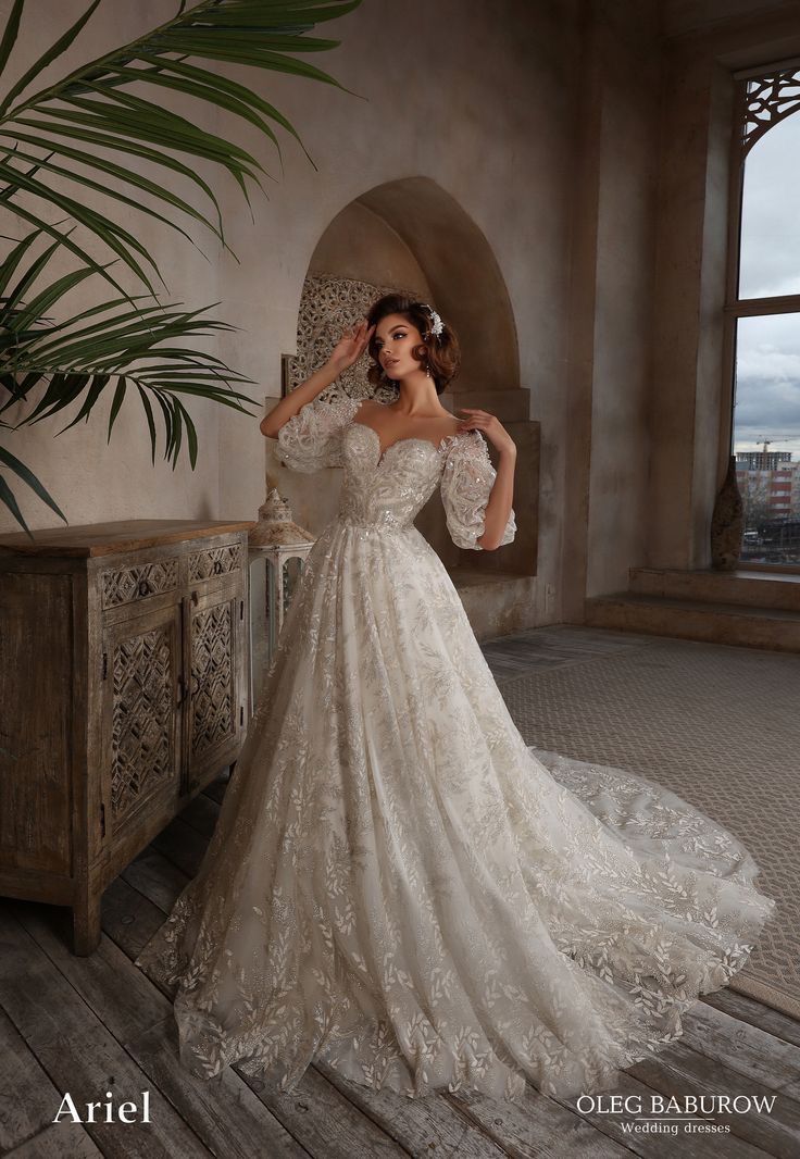 a woman in a wedding dress standing on a wooden floor next to a potted plant