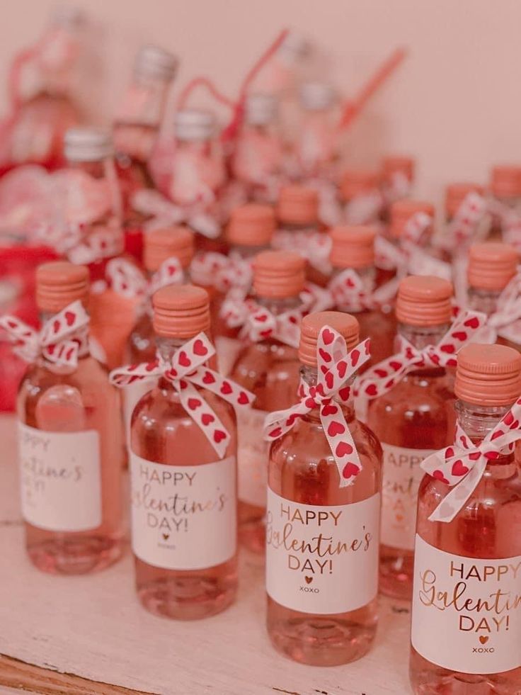 several bottles of pink liquid are on a table with red and white ribbons tied around them