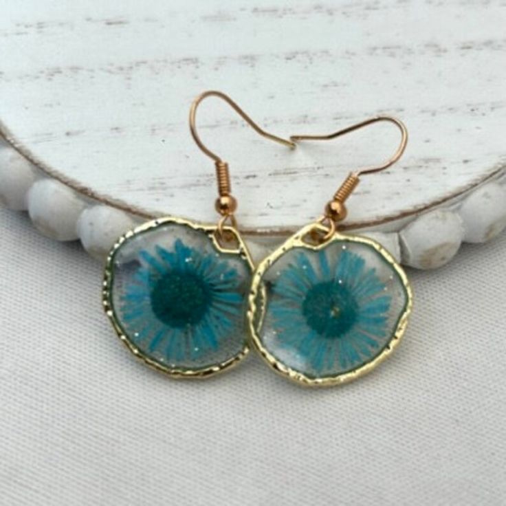 the earrings are made with glass and gold plated wire, which is decorated with blue flowers