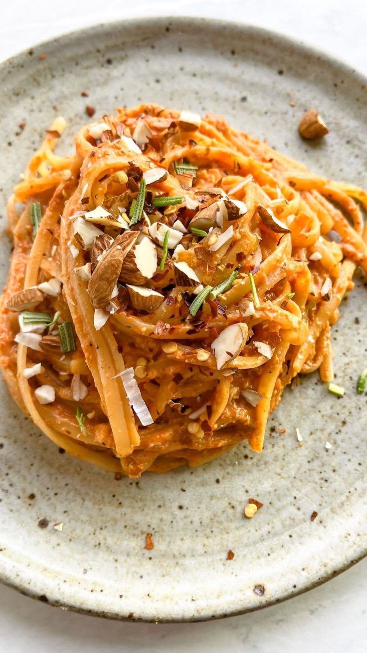 a white plate topped with pasta covered in sauce and garnished with chopped nuts