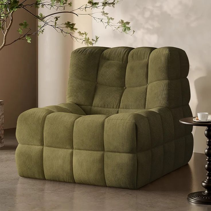 a green reclining chair sitting in front of a potted plant on top of a table