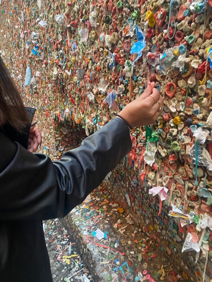 a woman pointing at a wall covered in hundreds of locks