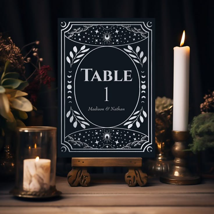 a table number sign sitting on top of a wooden table next to candles and flowers