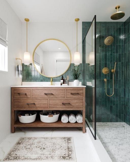 a bathroom with green tiled walls and wooden cabinetry, along with a large round mirror above the sink