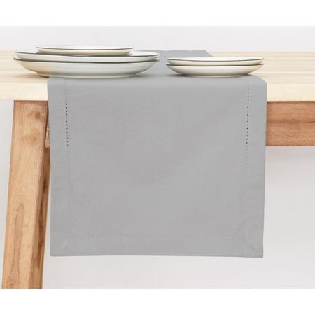 two plates are sitting on the edge of a wooden table with gray linen napkins