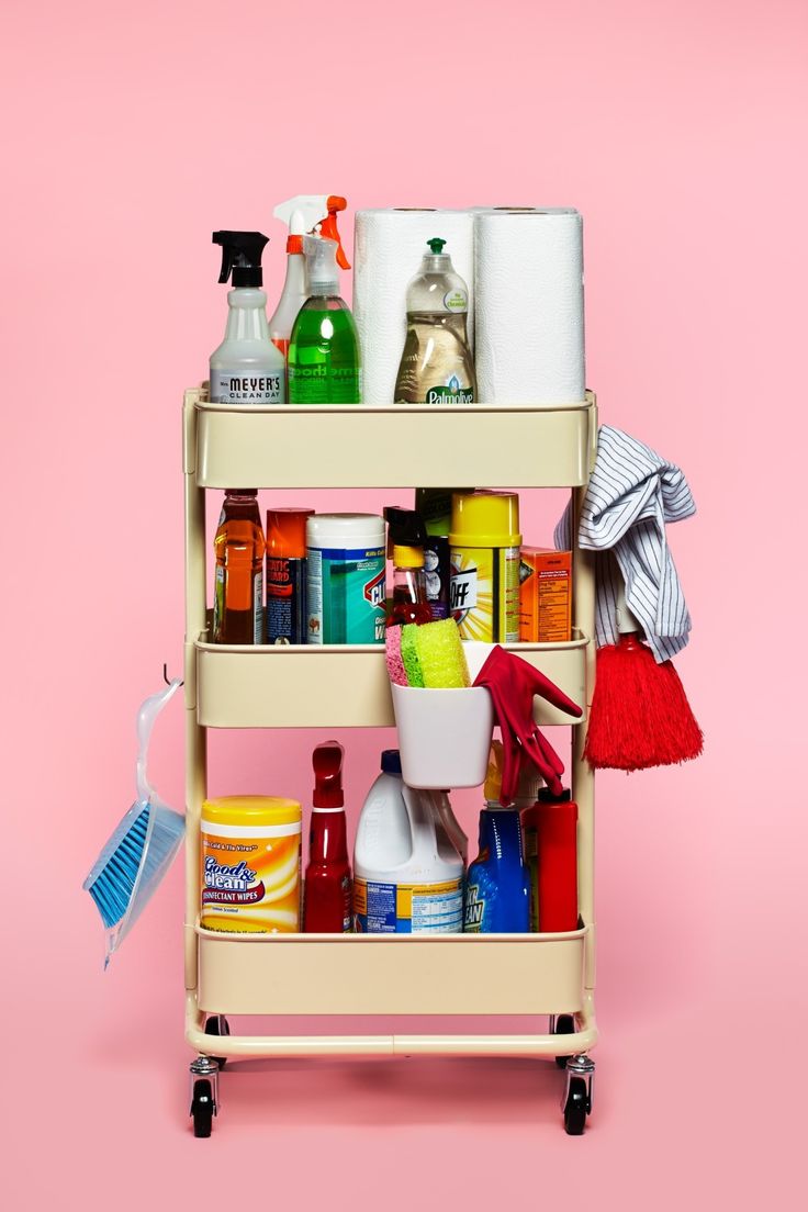 a cart with cleaning products on it against a pink background