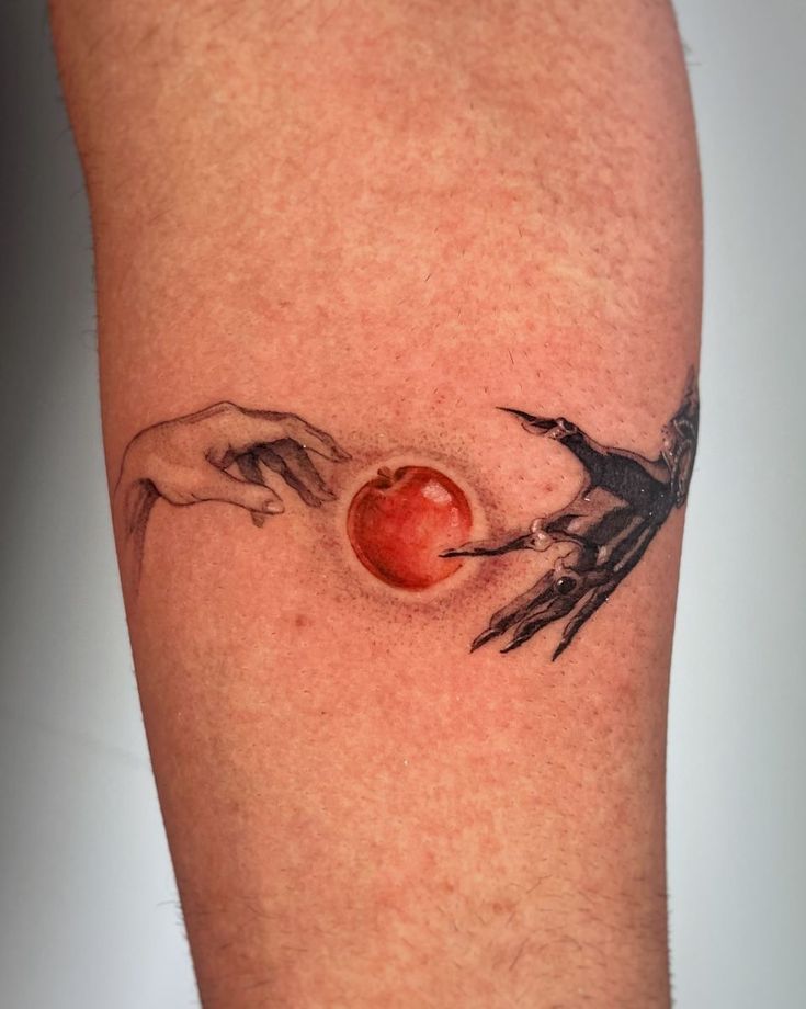 a tattoo on the leg of a man with two hands reaching for an apple