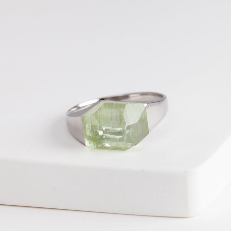 Description Bororo's signature rock ring in a smaller size with a beautiful green aquamarine stone from Brazil. Mini rock rings are perfect for those who love the innovative design of rock rings and want to wear it every day. The irregular geometrical cut of the stone makes this ring edgy and contemporary. The pieces in the rock series are made by applying the Japanese traditional method 'Dozuri'. This technique shapes the ring when the stone and metal are attached to create its seamless look. Every single rock ring is unique because from the designer's selection of the rough stone to the traditional craftsman cutting and smithing the ring, every action is based on the shape of each individual stone. Details Rhodium Plated Sterling SilverGreen Aquamarine – Approximately 11 x 8mm (size vari Modern Green Birthstone Jewelry, Modern Green Crystal Ring As Gift, Modern Green Crystal Ring As A Gift, Modern Green Crystal Ring For Gift, Modern Peridot Jewelry For Gift, Modern Peridot Jewelry As A Gift, Modern Peridot Jewelry For Formal Occasions, Modern White Gold Crystal Ring With Gemstone, Modern Green Emerald Promise Ring