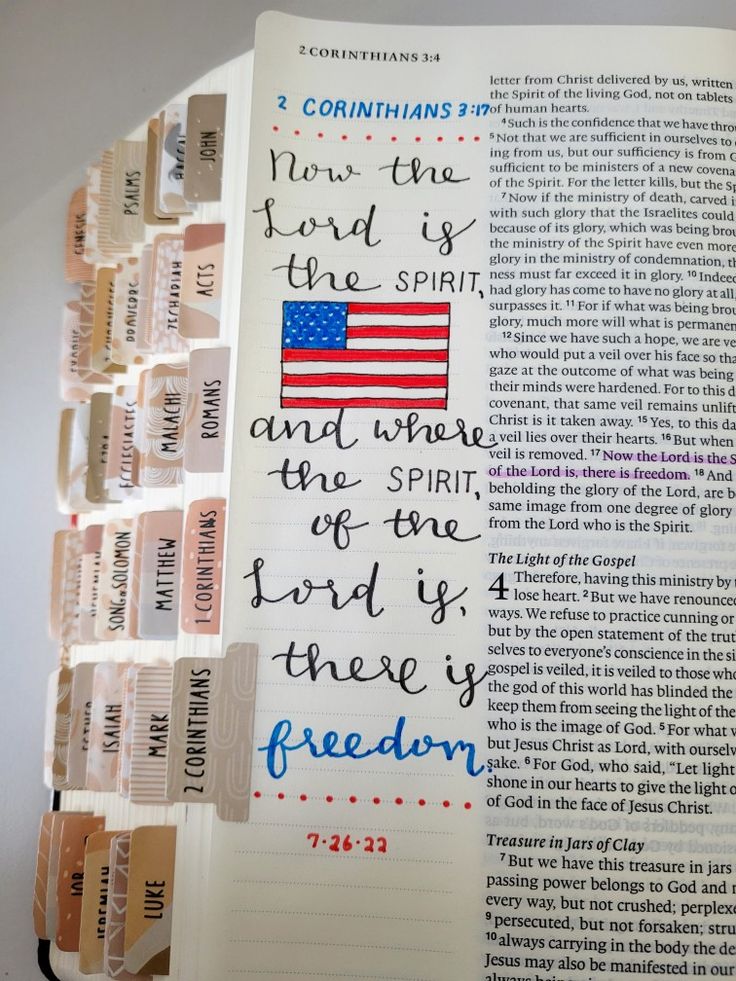 an open bible with the american flag on it and handwritten verses in different colors