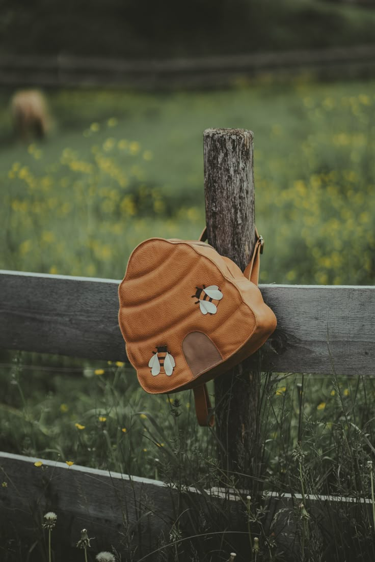 a brown purse hanging on the side of a wooden fence in front of a field