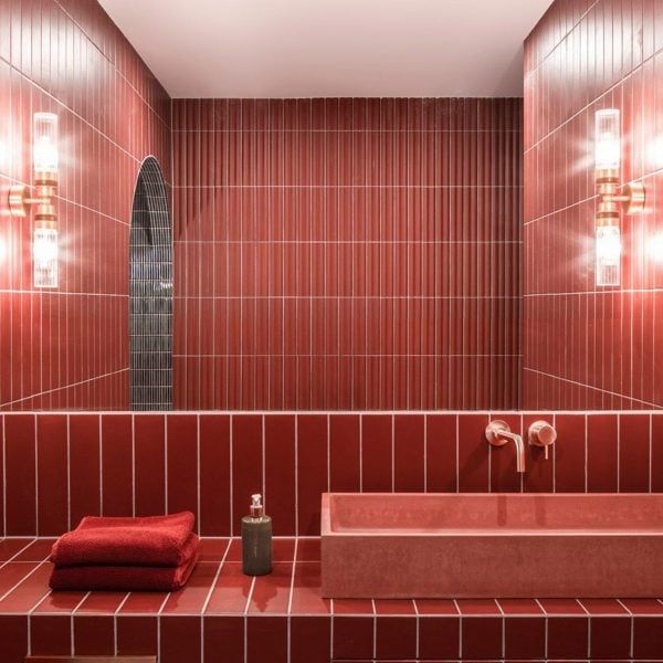 a red tiled bathroom with two sinks and mirrors