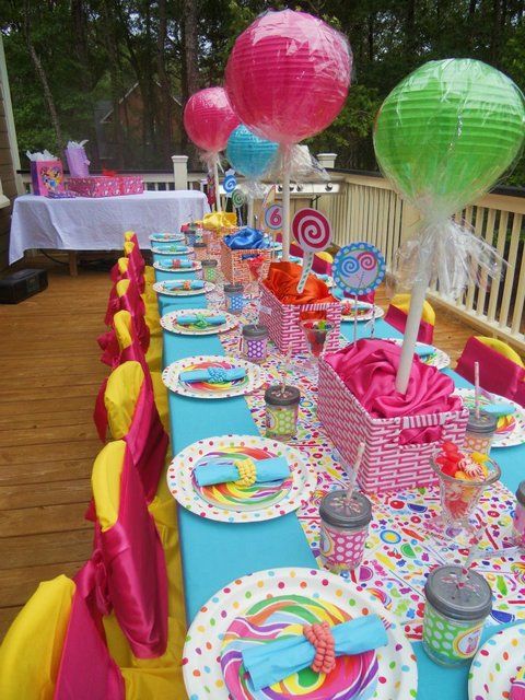 a long table is set up with paper lanterns and candy bar wrappers for an outdoor birthday party