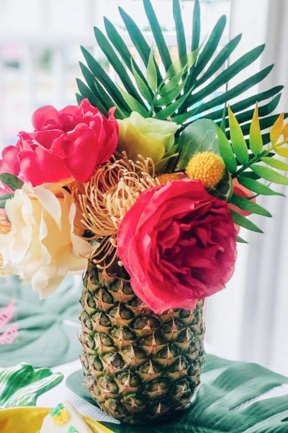 a pineapple vase filled with flowers on top of a table