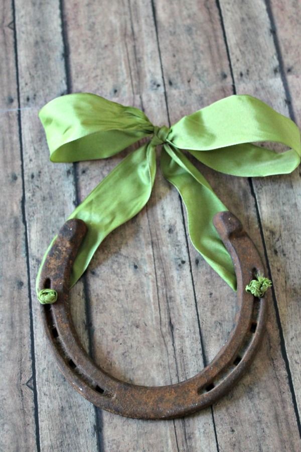 an old horseshoe with a green bow on it sitting on a wooden floor next to a pair of scissors