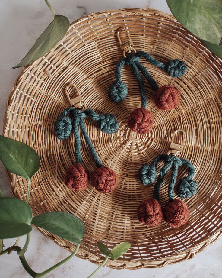 four crocheted balls of yarn sitting on top of a wicker basket next to green leaves