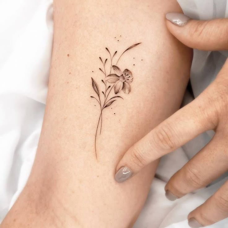 a woman's arm with a small flower tattoo on the left side of her body