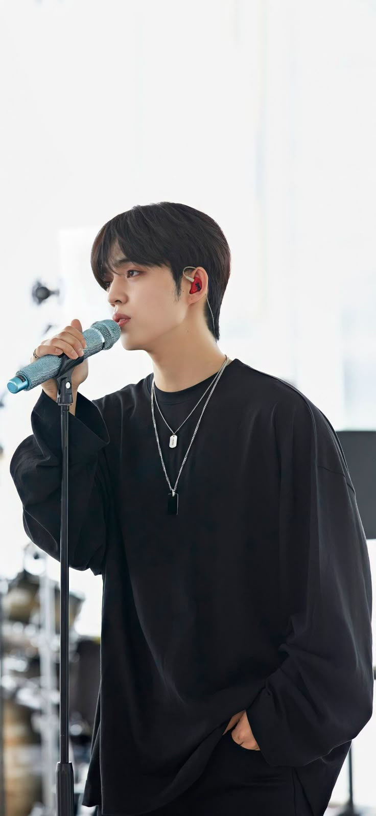 a male in a black shirt is holding a microphone and looking at the side of his face