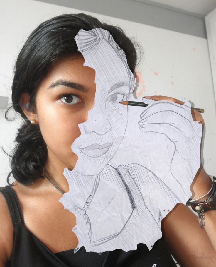 a woman holding up a piece of paper to her face with the image of a woman's face drawn on it