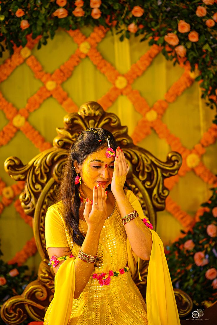 a woman in yellow dress sitting on a chair with her hands clasped to her face