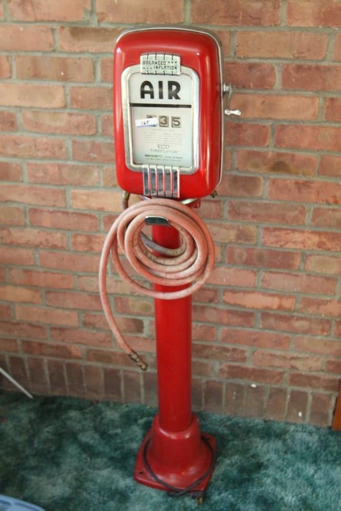 an old fashioned red gas pump sitting in front of a brick wall with a hose attached to it