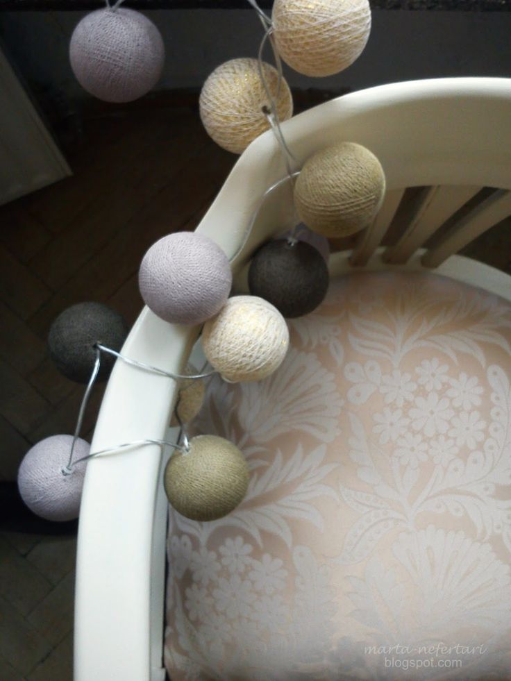 some balls are hanging from the back of a chair and it looks like they have been made out of yarn