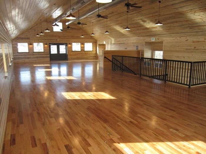 an empty gym with hard wood flooring and ceiling fan light shades on the windows