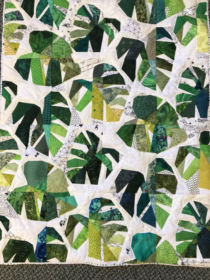 a green and white quilt with leaves on it