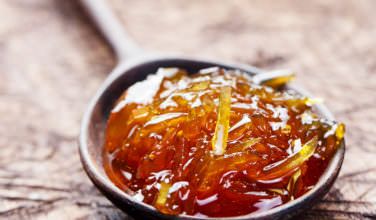 a spoon filled with jelly on top of a wooden table