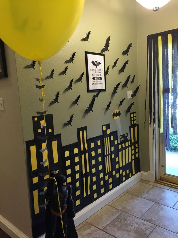 a room decorated for halloween with bats on the wall and yellow balloons in the air