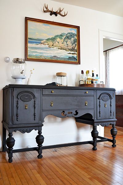 an old dresser is painted black and sits on the floor in front of a doorway